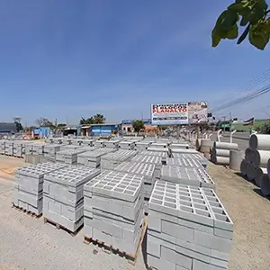 imagem com diversos blocos de concreto empilhados e enfileirados, em cima de pallets, ao longo do terreno de pedra britada