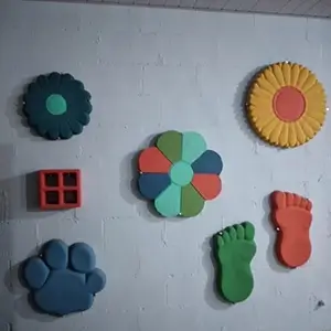 imagem com vários enfeites coloridos de jardim, em formas e cores distintas, presos em uma parede branca