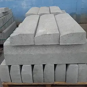 Imagem com diversos blocos de meio fio de rua empulhados e enfileirados, sobre pallets, no terreno externo