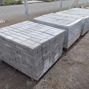 imagem de um galpão com diversos pavers de concreto pré-fabricadas empilhados em cima de um pallet e envoltos em plástico transparente
