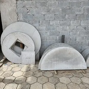 imagem com tampas de concreto encostadas e enfileiradas numa parede de tijolos cinzas